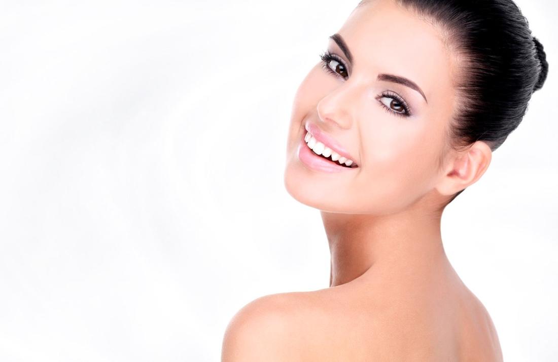 A young woman with glowing skin smiling after a Rejuvenating Chevy Chase facial spa treatment session.